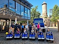 Sechs Spielzeug-Unimogs vor einem echten Unimog bei der Burg Nohfelden. Mit Kindern, KiTa-Leitung, Bürgermeister und THW-Helfenden